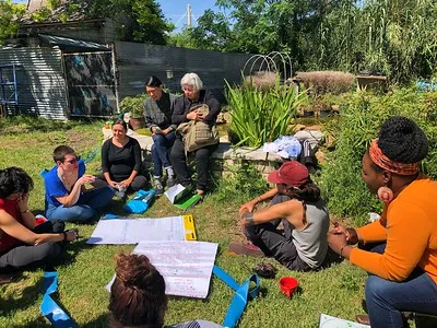 A multicultural group sitting in grass writing on large pieces of paper