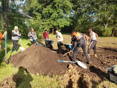 Multicultural group shoveling a large rich pile of soil