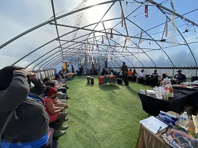 Clear Greenhouse with people sitting in chairs forming an oval throughout the greenhouse